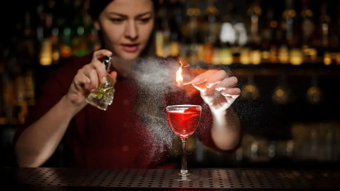 Barmaid flambant un zeste au-dessus d'un cocktail