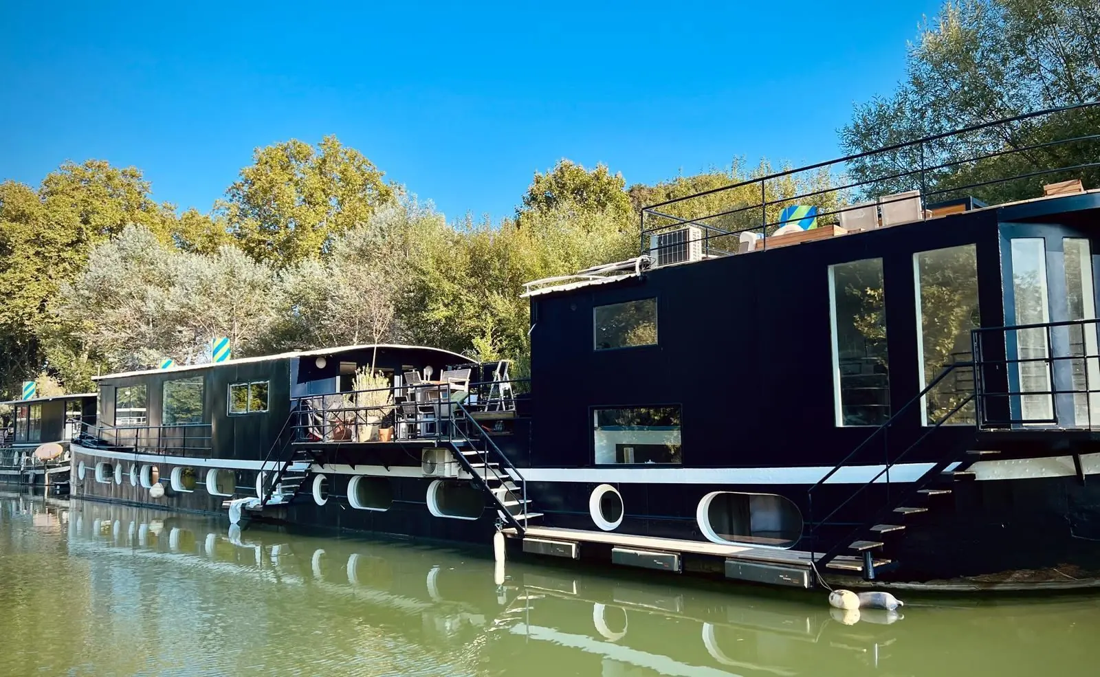 La péniche au soleil vue depuis la berge, avec son rooftop